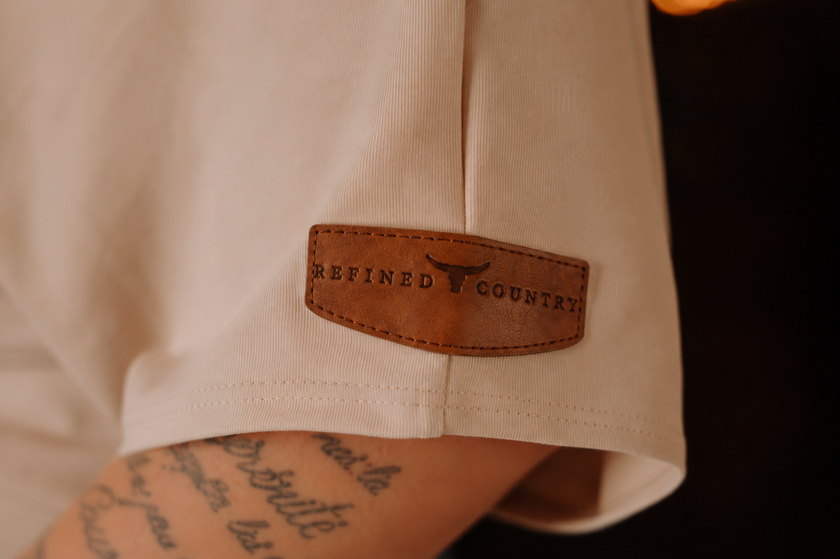 Détail de la pièce de cuir sur manche gauche T-Shirt épaule dénudéee